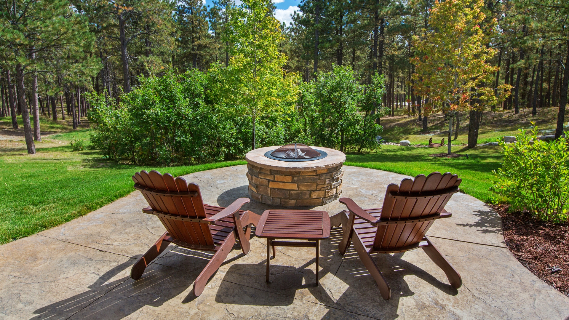 A patio and fire pit built by our team overlooking trees in Greenwich, CT.