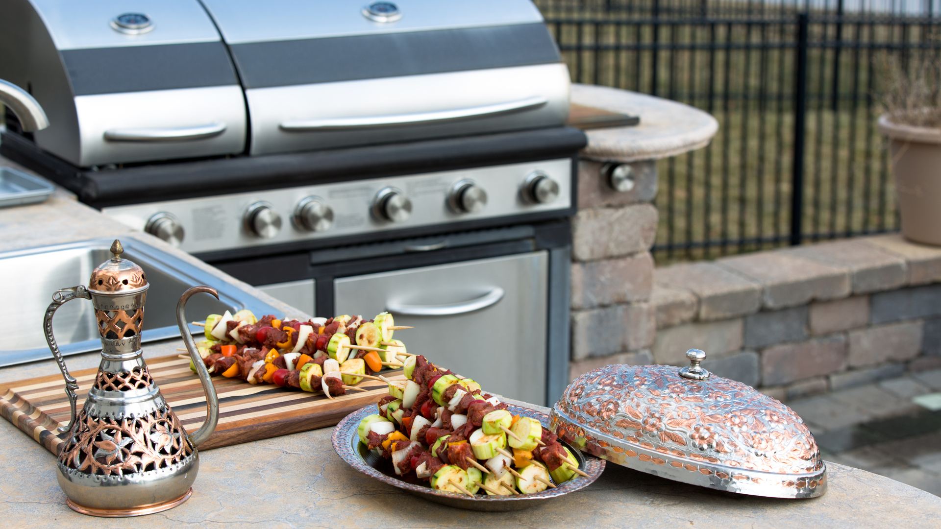 Raw kabobs on an outdoor kitchen counter and grill built by our team in Princeton, NJ.