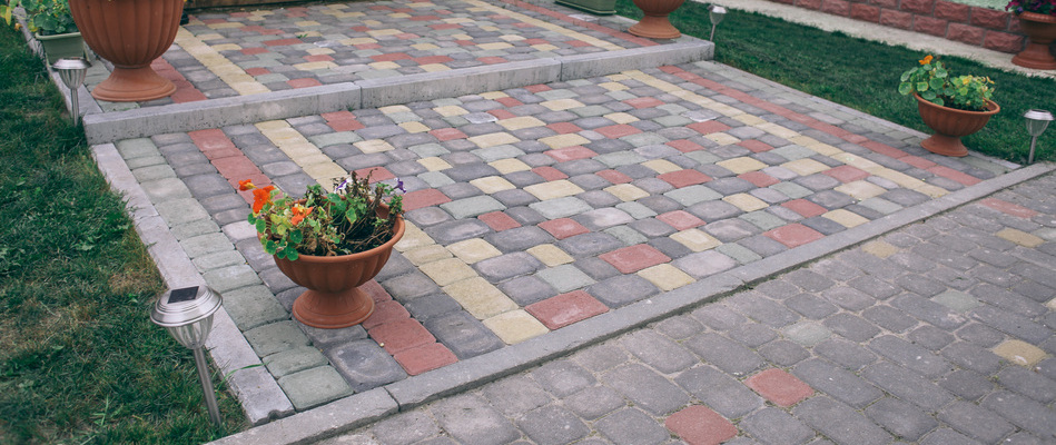 A paver patio with red, yellow, and green pavers installed by a home in Newark, NJ.