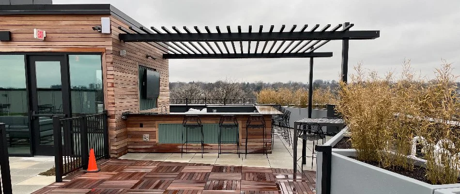 Commercial rooftop with an outdoor kitchen and black pergola.