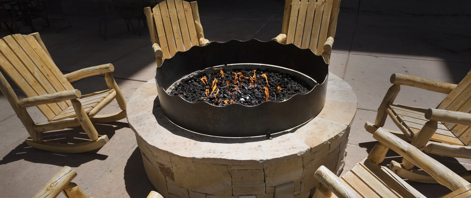 A gas fire pit topped with black rocks installed by our team on property in New Rochelle, NY.