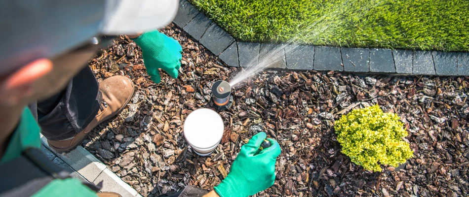 A professional checking an irrigation sprinkler head in Alpine, NJ.