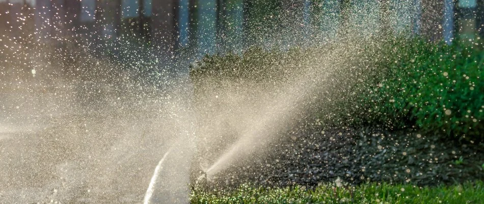 A sprinkler irrigation system watering a lawn and landscape bed on a commercial property in New Haven County, CT.