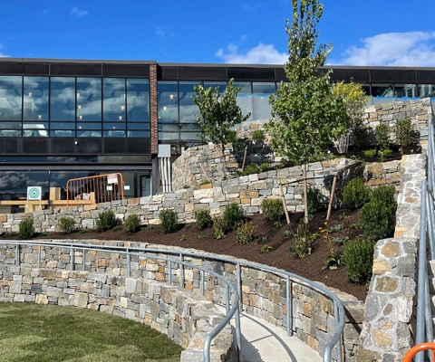 Sloped property with retaining wall and landscape beds installed in New York.